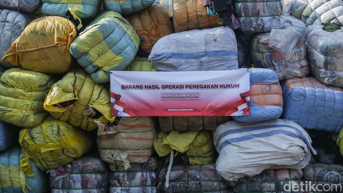 Penampakan Barang Senilai 46 M yang Disita Satgas Impor Ilegal Petugas bersenjata menjaga barang ilegal sitaan di Penimbunan Pabean Bea dan Cukai, Cikarang, Selasa (6/8/2024).