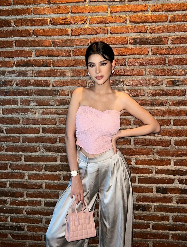 Atasan strapless pink dengan aksen wrapped memberi kesan feminin. Untuk tampilan lebih stunning, wanita 23 tahun ini memadukannya dengan celana oversized warna silver metalik. Micro bag puff melengkapi penampilannya. Foto: Instagram/@ritassyawellgreat