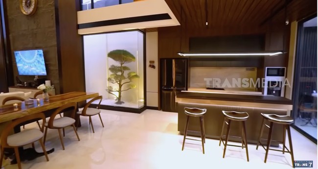 Ruang keluarga menyatu dengan dapur dan area makan. Di salah satu sudut, terdapat taman mungil estetis yang dihiasi pohon cemara udang. (Foto: YouTube/Trans7 Official)