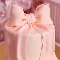 Tak hanya satu, kue lain bermodel simpel dengan bentuk pita berwarna merah muda pada bagian atasnya juga tampak ikut menyambut kelahiran baby R. Foto: Instagram/@princessyahrini