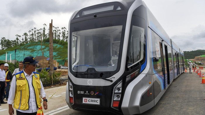 Ini Potret Kereta Tanpa Rel yang Mau Dijajal di IKN Ketua Satgas Pelaksanaan Pembangunan Infrastruktur IKN Danis H Sumadilaga (kiri) berjalan di depan gerbong kereta otonom di IKN, Penajam Paser Utara, Kalimantan Timur, Selasa (6/8/2024). Menurut Dirjen Perkeretaapian Kementerian Perhubungan (Kemenhub) Mohamad Risal Wasal, uji kelayakan jalan kereta otonom tersebut akan berlangsung selama lima hari untuk penyesuaian medan jalan yang dilalui saat perayaan HUT Ke-79 Kemerdekaan RI.