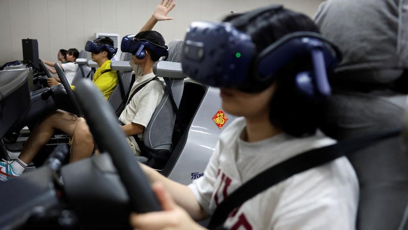 A driving instructor guides a student practising on a virtual reality (VR) car driving simulator at Eastern Pioneer Driving School in Beijing, China July 23, 2024. REUTERS/Florence Lo