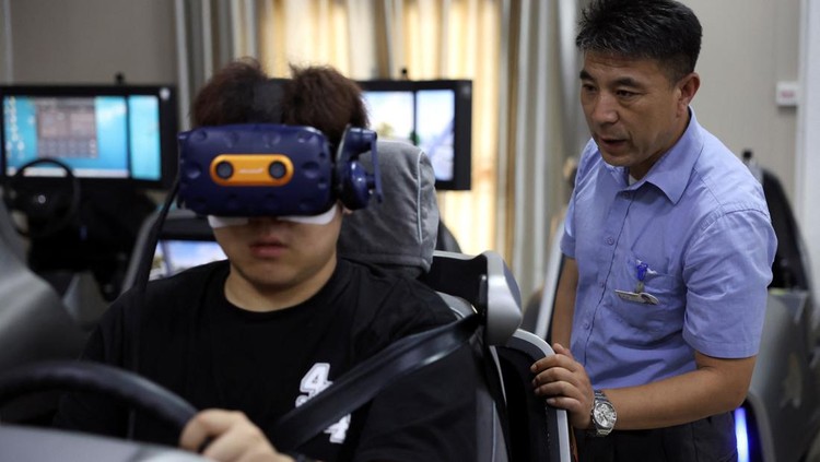A driving instructor guides a student practising on a virtual reality (VR) car driving simulator at Eastern Pioneer Driving School in Beijing, China July 23, 2024. REUTERS/Florence Lo