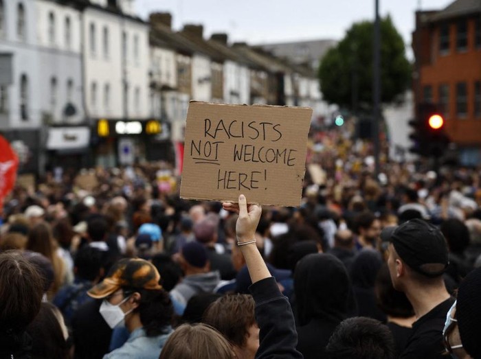 A protester holds a placard reading Racists not welcome here during a counter demonstration against an anti-immigration protest called by far-right activists in the Walthamstow suburb of London on August 7, 2024. Thousands of anti-racism protesters took to the streets in several English cities on Wednesday to oppose violent far-right demonstrations that have gripped the country in recent days. (Photo by BENJAMIN CREMEL / AFP)