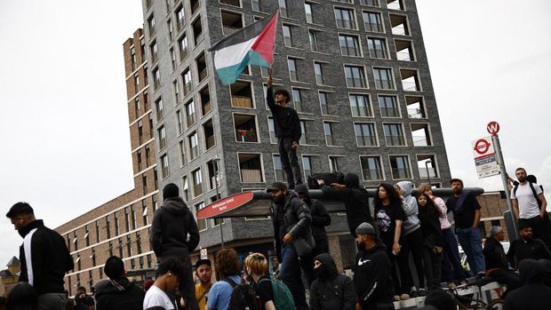 A protester waves a Palestinian flag during a counter demonstration against an anti-immigration protest called by far-right activists in the Walthamstow suburb of London on August 7, 2024. Thousands of anti-racism protesters took to the streets in several English cities on Wednesday to oppose violent far-right demonstrations that have gripped the country in recent days. (Photo by BENJAMIN CREMEL / AFP)