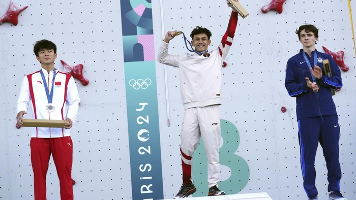 Gold medallist Veddriq Leonardo of Indonesia, center, poses on the podium with silver medallist Wu Peng of China, left, and bronze medallist Sam Watson of the United States after the men's speed final during the sport climbing competition at the 2024 Summer Olympics, Thursday, Aug. 8, 2024, in Le Bourget, France. (AP Photo/Tsvangirayi Mukwazhi)
