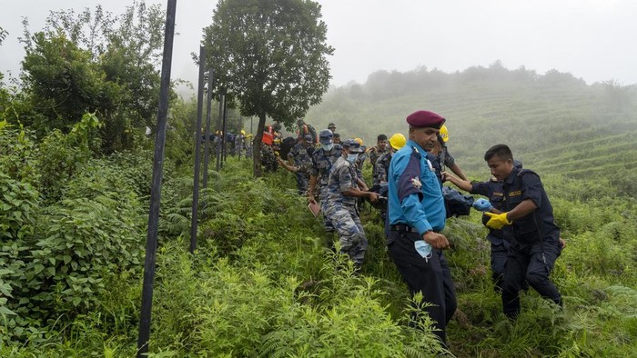 Rescuers carry the bodies of four Chinese passengers and the pilot from Nepal on the site of crashed helicopter of the Nepal-based Air Dynasty in Suryachaur area, northwest of Kathmandu, Nepal, Wednesday, Aug. 7, 2024. (AP Photo/Niranjan Shrestha)