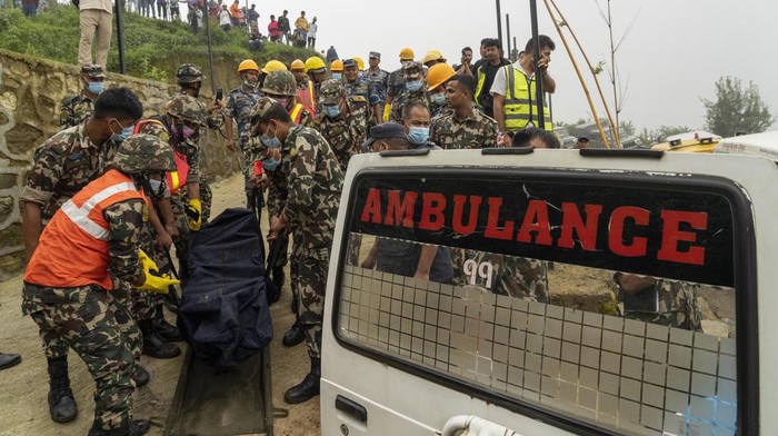 Rescuers carry the bodies of four Chinese passengers and the pilot from Nepal on the site of crashed helicopter of the Nepal-based Air Dynasty in Suryachaur area, northwest of Kathmandu, Nepal, Wednesday, Aug. 7, 2024. (AP Photo/Niranjan Shrestha)