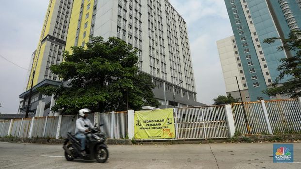 Pejalan kaki melintasi jembatan penyebrangan orang (JPO) dengan latar Wisma Atlet Kemayoran di Jakarta, Kamis (8/8/2024). (CNBC Indonesia/Faisal Rahman)