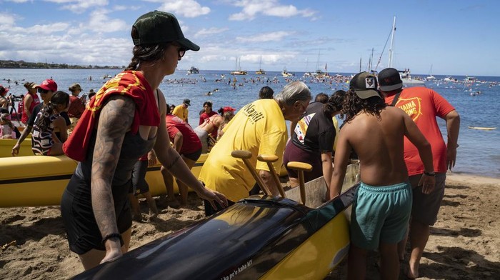Dalam memperingati satu tahun kebakaran hutan Lahaina di Hawaii, sejumlah warga melakukan aksi mendayung dan berselancar di laut lepas Lahaina. Ini potretnya.