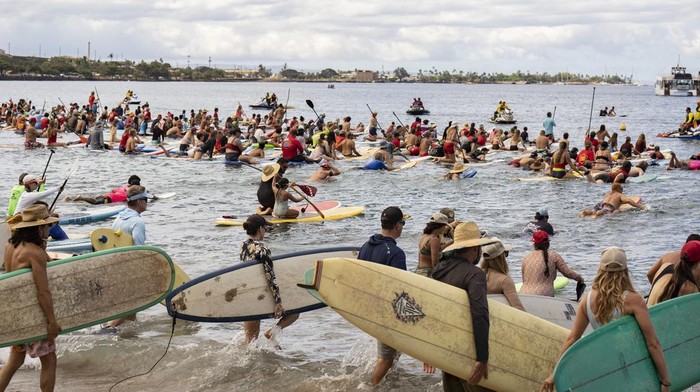 Dalam memperingati satu tahun kebakaran hutan Lahaina di Hawaii, sejumlah warga melakukan aksi mendayung dan berselancar di laut lepas Lahaina. Ini potretnya.