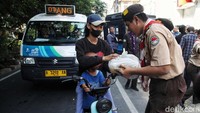 Para anggota Pramuka juga membagikan sembako kepada pengendara yang melintas.