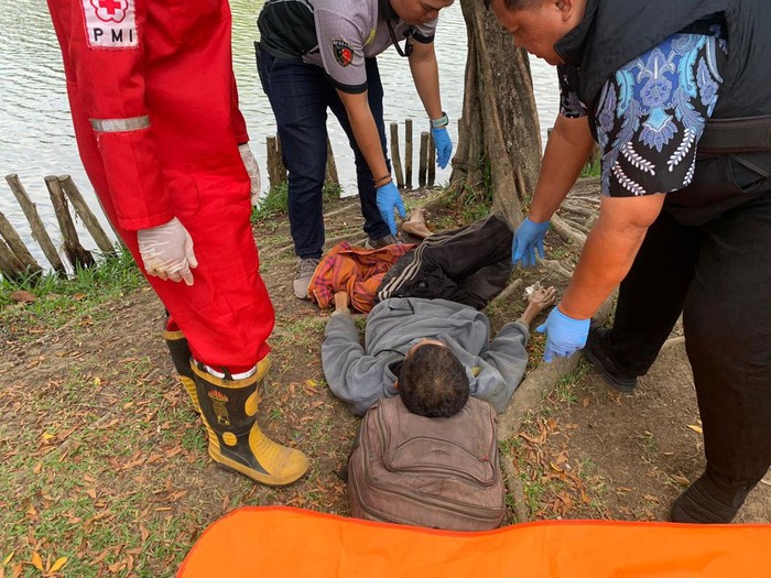 Polisi mengevakuasi jasad pria yang tergeletak di pinggir danau Kembang Iwak