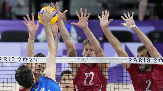 Left, Matthew Anderson, Maxwell Holt, and Aaron Russell, of the United States, block a ball during the men's bronze medal volleyball match between the United States and Italy at the 2024 Summer Olympics, Friday, Aug. 9, 2024, in Paris, France. (AP Photo/Dolores Ochoa)