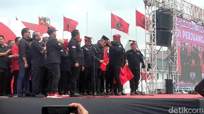 Ketua DPP PDIP Bidang Kehormatan Komarudin Watubun memakaikan peci hitam ke Edy Rahmayadi. (Nizar Aldi/detikSumut)