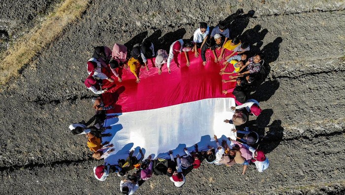 Sejumlah anak membentangkan bendera Merah Putih saat mengikuti kegiatan Sapa Desa di Ngluyu, Nganjuk, Jawa Timur, Minggu (11/8/2024). Aksi membentangkan bendera Merah Putih di salah satu daerah pelosok di Nganjuk tersebut merupakan bentuk upaya pemuda setempat untuk menanamkan semangat kemerdekaan dan cinta tanah air kepada masyarakat khususnya anak-anak di desa itu. ANTARA FOTO/Muhammad Mada/foc.