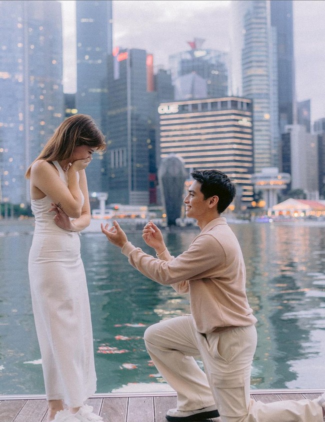Dalam unggahan Instagram pada Sabtu (10/8/2024), Cassandra Lee yang mengenakan gaun putih dan sepatu slip-on tampak terkejut saat Ryuken Lie berlutut dan menunjukkan cincin lamaran. Foto: Instagram/@cassandraslee