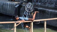 Peserta terjatuh saat mengikuti lomba ketangkasan bersepeda di sungai di Jogoloyo, Surabaya, Jawa Timur.