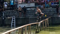 Ratusan peserta harus melintasi jembatan darurat dari papan kayu sepanjang 30 meter yang dibuat oleh panitia.