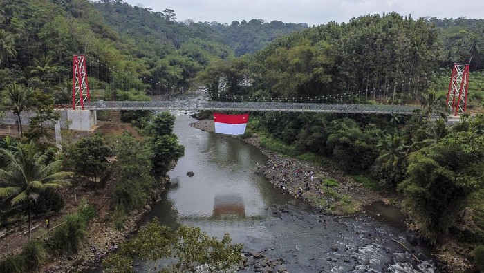 Melihat Gladi Bersih Upacara HUT RI di Jembatan Gantung Sungai Citanduy Foto udara warga RW 07 mengibarkan bendera merah putih pada gladi bersih upacara HUT ke-79 Kemerdekaan RI di Jembatan Gantung Sukamenak, Kampung Benteng, Kecamatan Purbaratu, Kota Tasikmalaya, Jawa Barat, Minggu (11/8/2024). Upacara yang diikuti warga lingkungan bantaran Sungai Citanduy itu, dilakukan dengan membentangkan bendera merah putih berukuran 60 meter persegi di Jembatan Gantung Sukamenak yang menghubungkan Kota Tasikmalaya dengan Kabupaten Ciamis. ANTARA FOTO/Adeng Bustomi/foc.