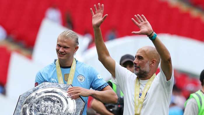 Soccer Football - Community Shield - Manchester United v Manchester City - Wembley Stadium, London, Britain - August 10, 2024 Manchester Citys Erling Braut Haaland and manager Pep Guardiola celebrate with the trophy after winning the Community Shield REUTERS/Toby Melville