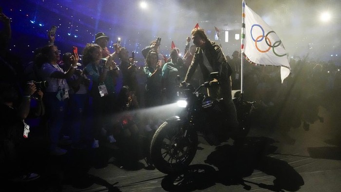 Tom Cruise rides a motorbike with the Olympic flag attached during the 2024 Summer Olympics closing ceremony at the Stade de France, Sunday, Aug. 11, 2024, in Saint-Denis, France. (AP Photo/Ashley Landis)