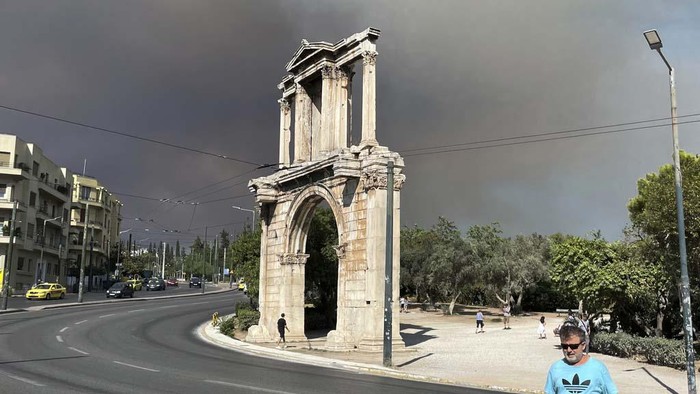 Smoke from wildfires is seen above the Greek parliament building in central Athens, Sunday, Aug. 11, 2024, after a blaze northeast of the capital forced evacuations in the area. (AP Photo/Derek Gatopoulos)