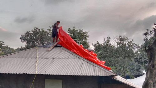 Warga menutup rumah dengan terpal warna merah karena seng karat dan bocor, Minggu (11/8/2024)