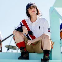 Billie Eilish memadukan kaus putih oversized bermotif garis diagonal biru-merah dengan celana pendek warna khaki. Topi baseball dan kacamata melengkapi penampilannya. Foto: Emma McIntyre/Getty Images for LA28