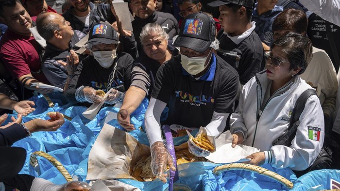 Mexico Taco Record A taqco vendor hands out tacos from her basket during a record-breaking event for the most tacos served in one hour β 30,000 β at the Angel of Independence monument in Mexico City, Sunday, Aug. 11, 2024. (AP Photo/Aurea del Rosario)