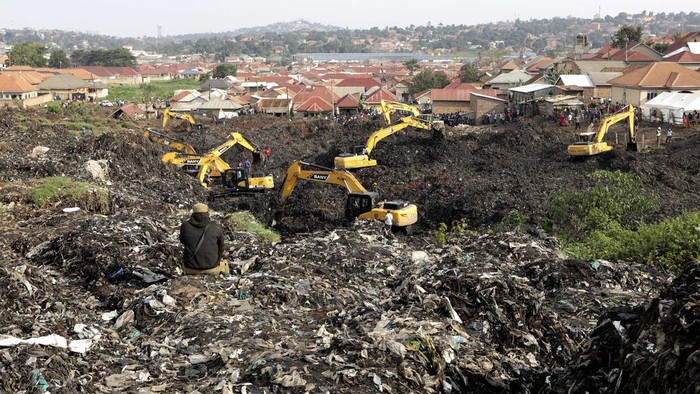 Potret Gunung Sampah di Uganda Longsor, 18 Orang Tewas Onlookers watch as workers search for survivors at the site of a collapsed landfill in Kampala, Uganda, Sunday, Aug. 11, 2024. (AP Photo/Hajarah Nalwadda)