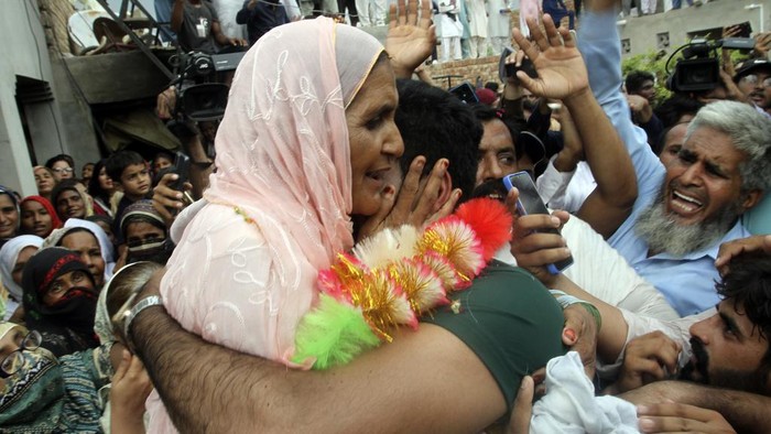 Men's javelin gold medalist, Arshad Nadeem of Pakistan, centre, waves to people outside his village in Mian Channu, Khanewal district, of Pakistan, Sunday, Aug. 11, 2024. (AP Photo/Asim Tanveer)