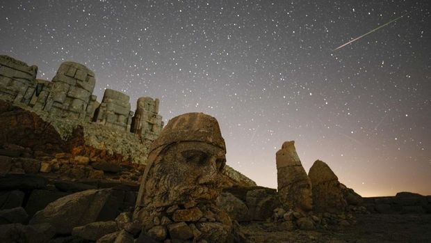 Patung-patung kuno terlihat selama hujan meteor Perseid di puncak Gunung Nemrut di tenggara Turki, Minggu, 11 Agustus 2024. Bertengger di ketinggian 2.150 meter (lebih dari 7.000 kaki), patung-patung tersebut merupakan bagian dari kompleks kuil dan makam yang dibangun oleh Raja Antiochus I, dari kerajaan Commagene kuno, sebagai monumen untuk dirinya sendiri. (AP Photo/Emrah Gurel)