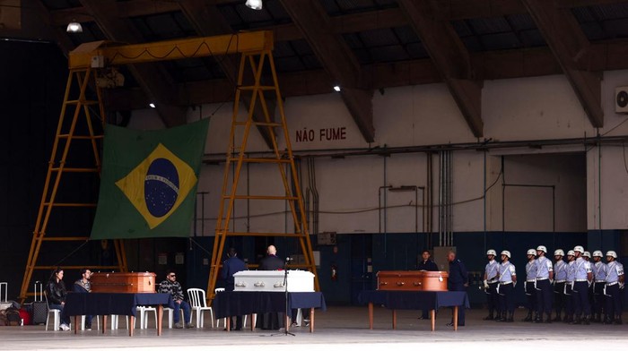 A priest talks to relatives of victims of the airplane crash that killed 62 people, during a tribute, before the coffins are delivered to their hometown, in Guarulhos, Brazil, August 13, 2024. REUTERS/Carla Carniel