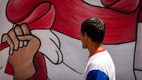 Warga berjalan di samping mural bertema kemerdekaan di Kelurahan Purwosari, Semarang, Jawa Tengah, Rabu (14/8/2024).