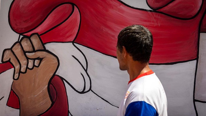 Seorang warga bersantai dengan katar belakang mural bertema kemerdekaan di Kelurahan Purwosari, Semarang, Jawa Tengah, Rabu (14/8/2024). Warga dari sejumlah perkampungan di Kota Semarang menghiasi lingkungan mereka dengan berbagai macam seni dekorasi seperti tulisan mural bertema kemerdekaan sebagai wujud rasa cinta terhadap perjuangan para pahlawan dalam merebut kemerdekaan sekaligus untuk memeriahkan HUT ke-79 Republik Indonesia. ANTARA FOTO/Aji Styawan/nym.