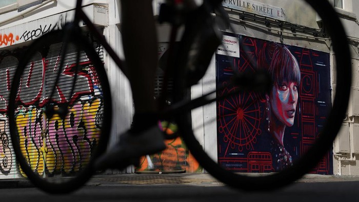 A new mural portrait of Taylor Swift designed by Kate Clayton, who poses next to it, as it is unveiled in Shoreditch in east London, Tuesday, Aug. 13, 2024. (AP Photo/Alastair Grant)