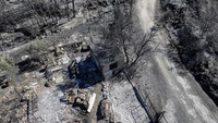 Lanskap yang hangus dan properti yang terbakar atau rusak parah menjadi pemandangan yang disaksikan banyak warga Rapentosa dan Varnavas pada Selasa (13/8), setelah api mencapai pinggiran kota utara Athena pada Senin sore. REUTERS/Fedja Grulovic