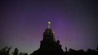 Aurora Borealis, yang juga dikenal sebagai Cahaya Utara, terlihat di atas Gereja Kelahiran Kristus saat hujan meteor Perseid tahunan di desa Gololobovo di wilayah Moskow, Rusia, Selasa (13/8/2024). (AP Photo/Pavel Bednyakov)