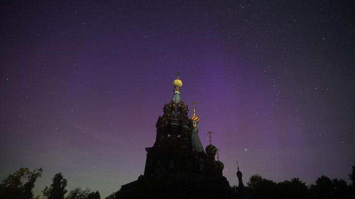 In this photo taken with long shutter speed, northern lights, or aurora borealis, are seen above the Church of the Nativity of Christ in Gololobovo village in Moscow region, Russia, Tuesday, Aug. 13, 2024. (AP Photo/Pavel Bednyakov)