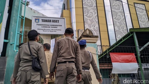 Satpol PP Lombok Barat memasang plang di lahan STIE AMM di Kota Mataram. (Ahmad Viqi/detikBali)