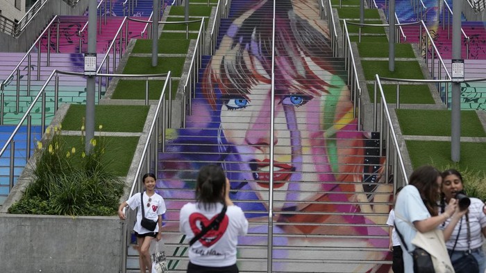 Fans pose by a Taylor Swift portrait painted on a stairway at Wembley Stadium in London, Wednesday, Aug. 14, 2024, ahead of a series of Taylor Swift concerts starting Thursday. (AP Photo/Alastair Grant)