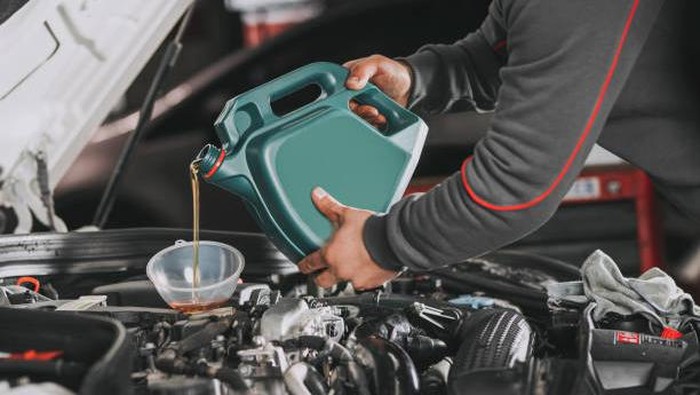 Pouring oil to car engine.