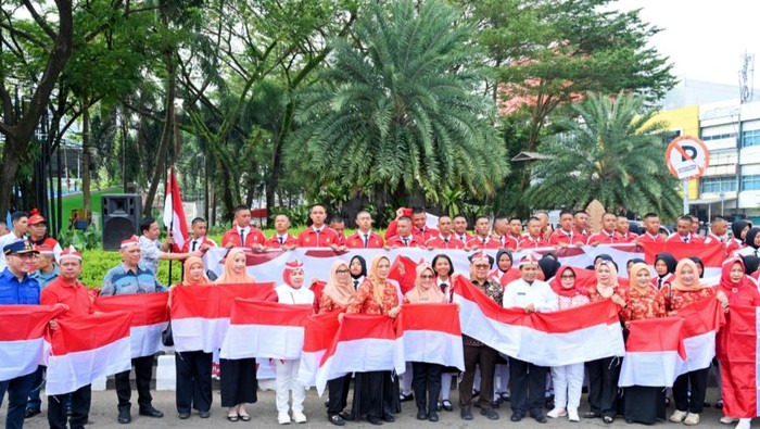 Pj Wali Kota Palembang membagikan ribuan bendera merah putih ke pengendara.