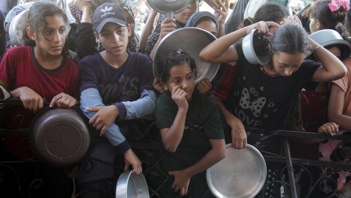 Palestinians wait to receive food cooked by a charity kitchen, amid a hunger crisis as conflict between Israel and Hamas continues, in the northern Gaza Strip August 14, 2024. REUTERS/Mahmoud Issa