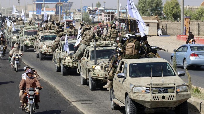Taliban fighters carry dummy yellow canisters intended to represent homemade explosives, as they celebrate the third anniversary of the withdrawal of US-led troops from Afghanistan, in Lashkar Gah, Helmand province, southwestern Afghanistan, Wednesda