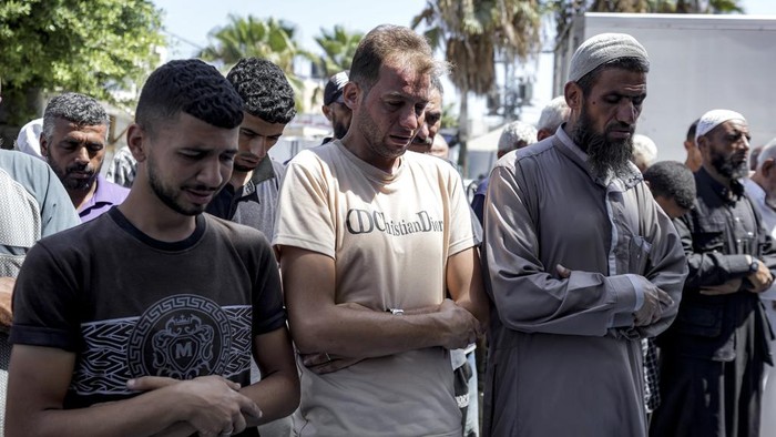 Mohammad Abu Al-Qumsan, Center, prays next to the bodies of his 4-day-old twin children, killed in the Israeli bombardment of the Gaza Strip, at a hospital in Deir al-Balah, Tuesday, Aug. 13, 2024. (AP Photo/Abdel Kareem Hana)