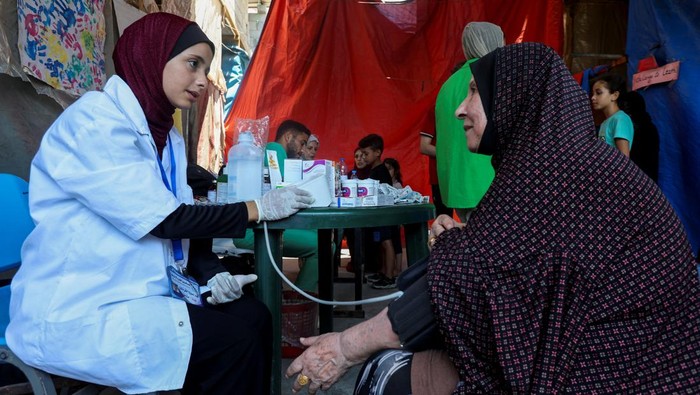 Lobna al-Azaiza, a Palestinian pediatrician providing free medical services to displaced Palestinians, examines a boy in a tent near her house, which was destroyed in an Israeli strike, in Deir Al-Balah in the central Gaza Strip, July 11, 2024. REUTERS/Ramadan Abed