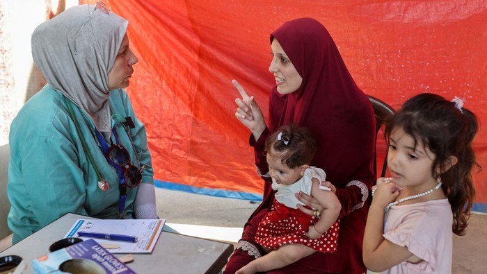Lobna al-Azaiza, a Palestinian pediatrician providing free medical services to displaced Palestinians, examines a boy in a tent near her house, which was destroyed in an Israeli strike, in Deir Al-Balah in the central Gaza Strip, July 11, 2024. REUTERS/Ramadan Abed
