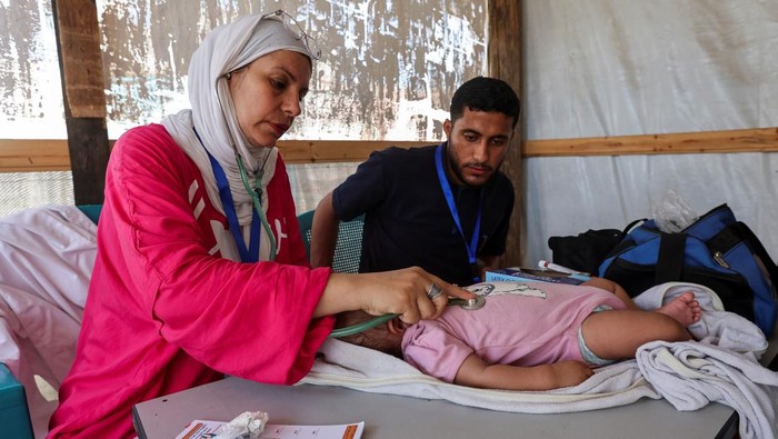 Lobna al-Azaiza, a Palestinian pediatrician providing free medical services to displaced Palestinians, examines a boy in a tent near her house, which was destroyed in an Israeli strike, in Deir Al-Balah in the central Gaza Strip, July 11, 2024. REUTERS/Ramadan Abed